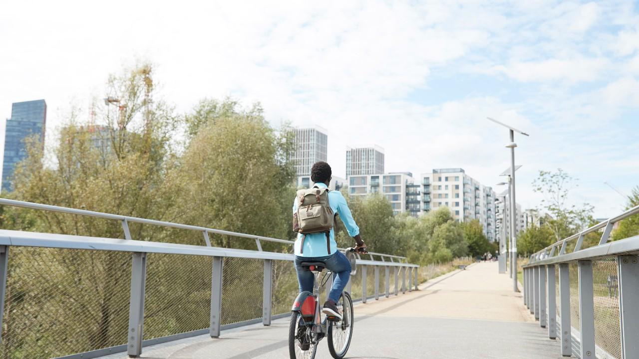 一位年轻的女士骑着自行车过桥进城.